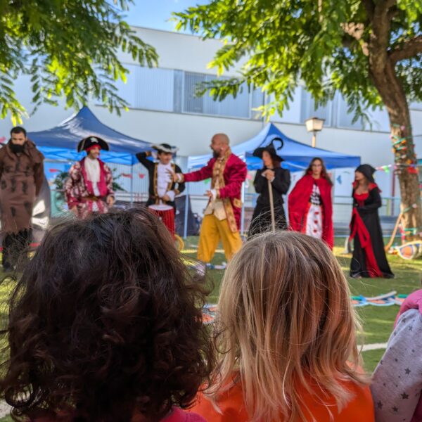 Niños y niñas de Educación Infantil observan una representación teatral con personajes de cuentos en el taller “Malvados de Cuentos”.